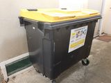 a black trash can with a yellow lid next to a white door