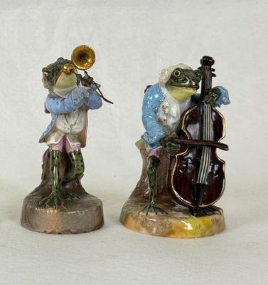 three figurines of a frog playing a musical instrument