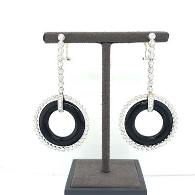 black and white earrings with a circular design hanging from a stand