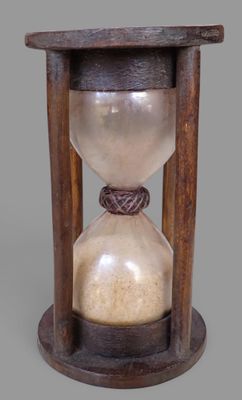 un vieux sablier avec un socle en bois sur fond gris