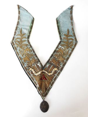 un gros plan d'un collier bleu et or sur fond blanc
