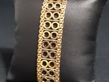 a close up of a gold bracelet on a pillow on a black surface