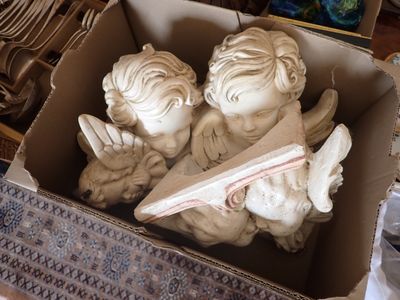 deux statues d'anges dans une boîte en carton posée sur une table