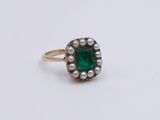 a close up of a ring with a green stone and pearls