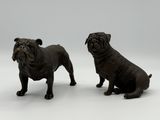 pair of black figurines of two dogs sitting on a white surface