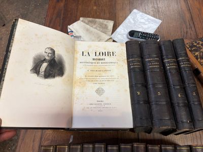 une personne tenant un livre sur lequel sont posés de nombreux autres livres