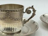 a silver cup and saucer sitting on a saucer