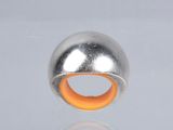 a silver and orange ring on a reflective surface