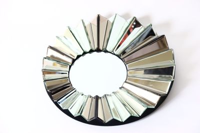 un miroir rond orné de nombreux miroirs, posé sur une surface blanche