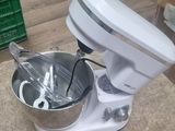 a mixer sitting on the floor next to a bowl of food