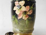 a black vase with pink flowers painted on it