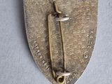 a close up of a metal pin with a cross on it