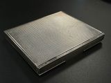 an old silver cigarette case sitting on top of a black table