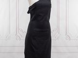 La robe est noire et présente une coupe asymétrique.
