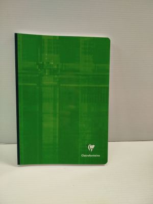 Le cahier vert est posé sur une table blanche, à côté d'une tasse de café.