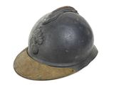 un vieux casque repose sur une surface blanche, surmonté d'une casquette marron
