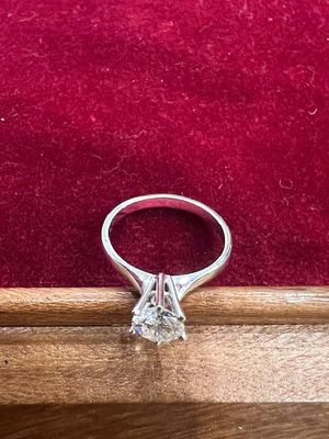 un gros plan d'une bague en diamant posée sur une boîte en bois