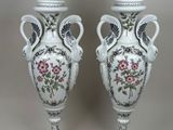 une paire de vases blancs ornés de motifs floraux, posés sur une table