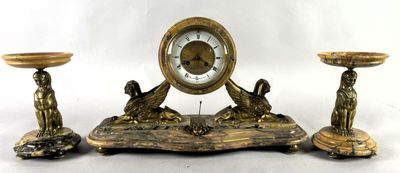 une horloge posée sur une table à côté de trois bougies