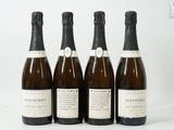 quatre bouteilles de vin sont alignées sur une surface blanche