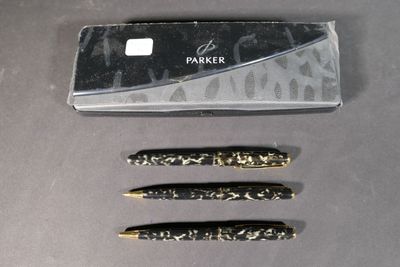 three pens are sitting on a table next to a package of paper