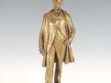 bronze statue of a man in a suit and tie standing on a pedestal