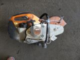 a chainsaw sitting on the ground next to a persons feet