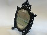 an antique mirror with a black frame sitting on top of a white surface