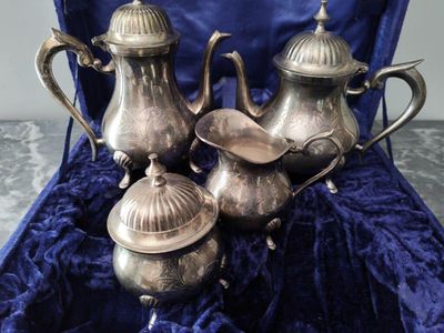 trois théières en argent rangées dans un étui en velours bleu