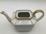 a white and gold teapot with a gold handle