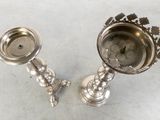 pair of silver candlesticks on a table with a white background