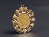 un gros plan d'une pièce d'or sertie dans un pendentif, sur un fond noir
