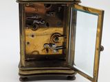 a small brass clock with a mirror on top of it