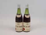 deux bouteilles de vin posées l'une à côté de l'autre sur une surface blanche