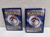 two pokemon cards are sitting next to each other on a white surface
