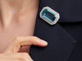the lapel of a woman wearing a ring with a blue topaz stone