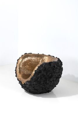 bol noir et doré posé sur une surface blanche, sur fond blanc