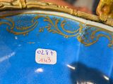 a close up of a blue and gold vase with a bird on it