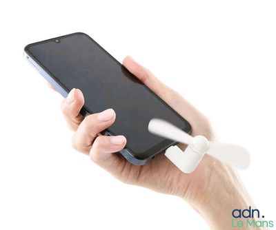 une personne tenant un téléphone portable auquel est fixé un ventilateur