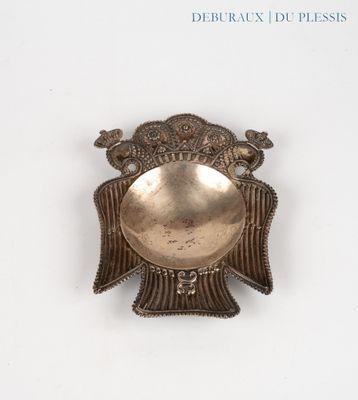 a silver plate with a bird on it on a white surface