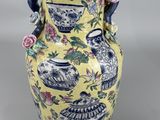 a yellow vase with blue and pink flowers on it