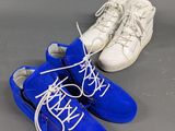 two pairs of blue sneakers with white laces on a gray surface