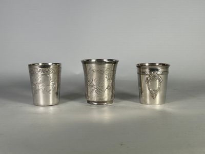 trois verres à shot en métal argenté posés sur une table