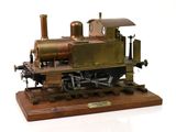une petite maquette de machine à vapeur posée sur un socle en bois