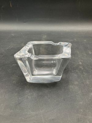 a glass ashtray on a table with a black background