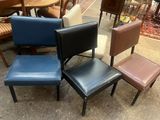 Plusieurs fauteuils en cuir de différentes couleurs sont disposés en cercle à même le sol.