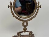 un petit miroir posé sur un pied, avec un homme en arrière-plan