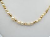 a necklace with pearls and gold beads on a mannequin