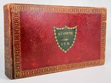 an old red book with gold trim and a shield on it