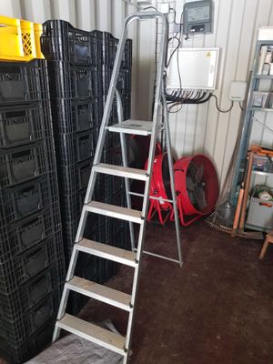 a ladder that is leaning against a wall next to a stack of crates